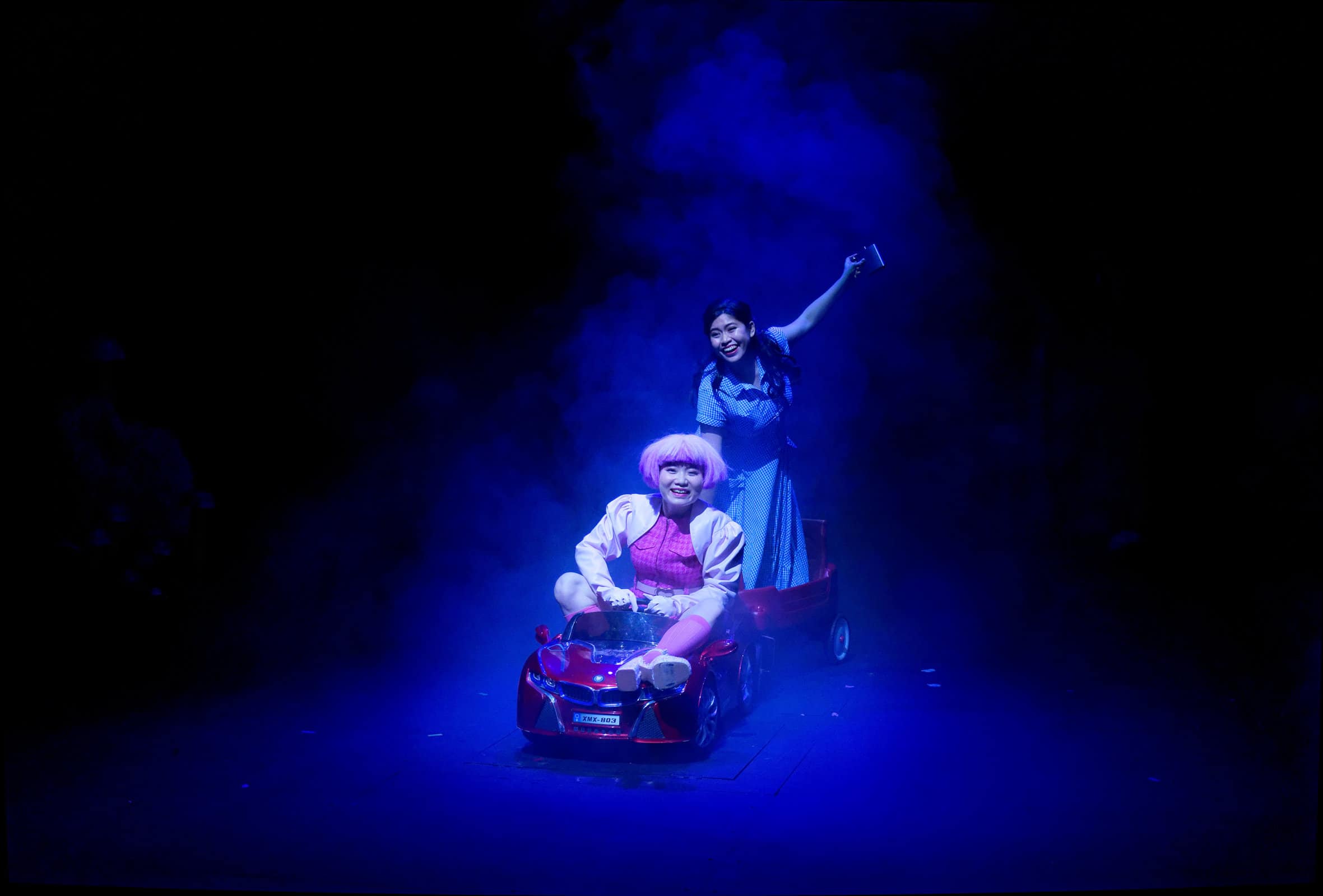 Tiara Yap as Jane and Michelle Hariff as Lisa in a child’s electric car
