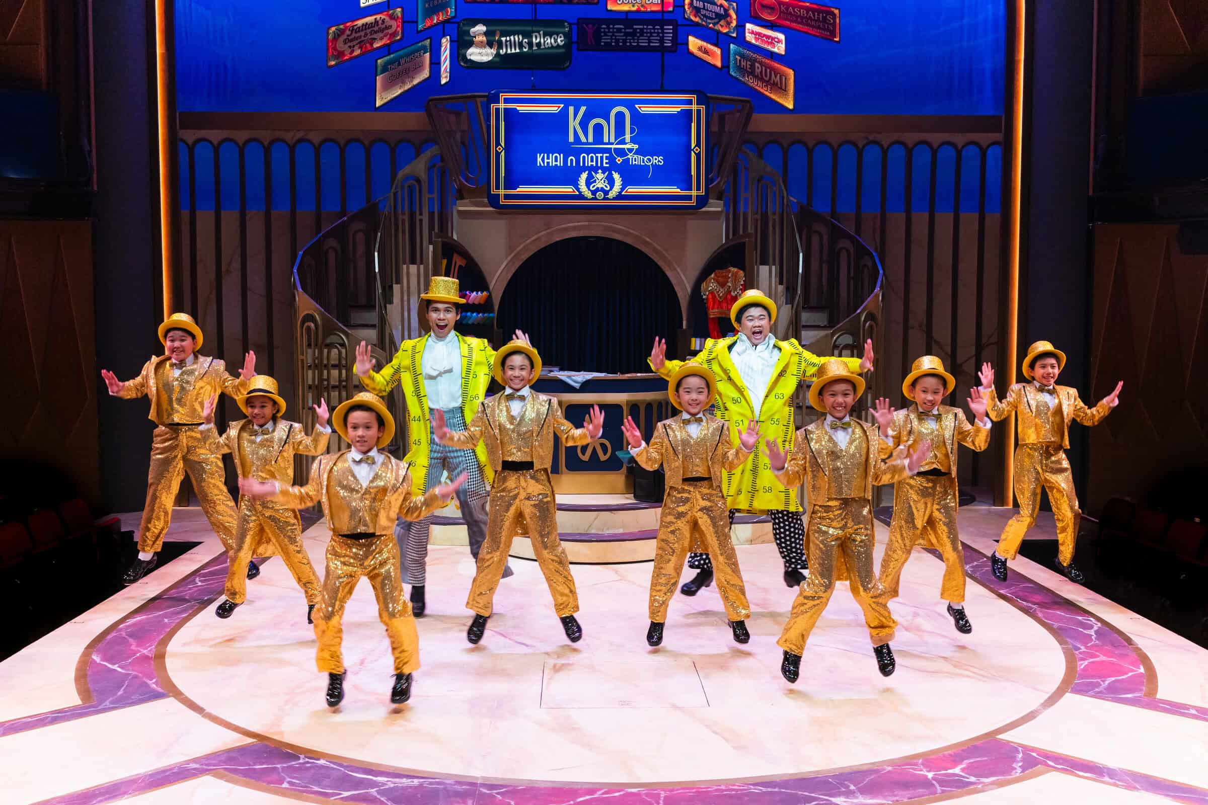 Rino Junior John as Nate, Izzul Irfan as Khai and the First Stage Kids dressed in gold and yellow, tap dancing on stage